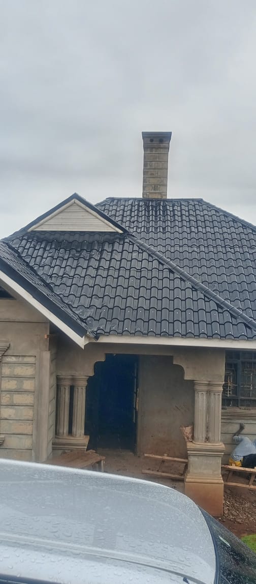 Completed black tile roof on residential house under construction — Everbest Mabati