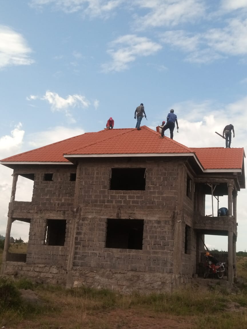 Orange stone-coated tiles being installed on two-storey house — Everbest Mabati